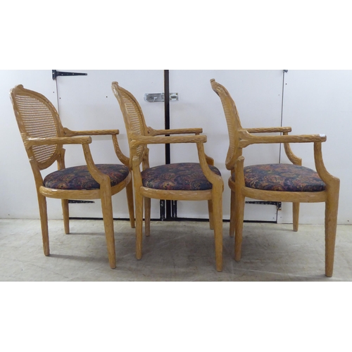 246 - A set of six modern natural oak effect framed dining chairs with a caned panel back, over a fabric c... 