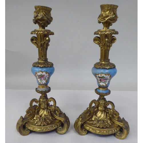 28 - A pair of late 19thC Continental decoratively cast gilt metal and painted porcelain candlesticks wit... 