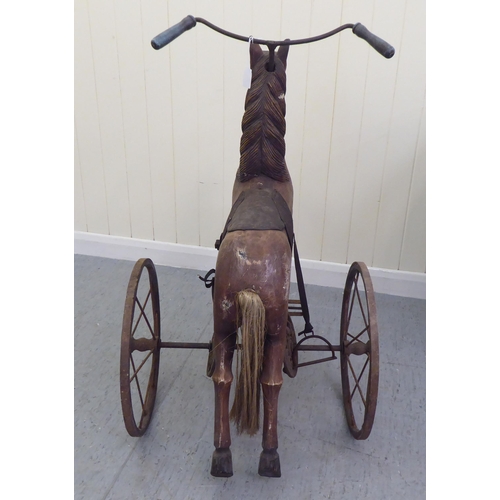 3 - A vintage pedal action, painted wooden toy horse, on three spoked wheels  approx. 30