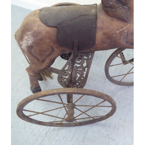 3 - A vintage pedal action, painted wooden toy horse, on three spoked wheels  approx. 30