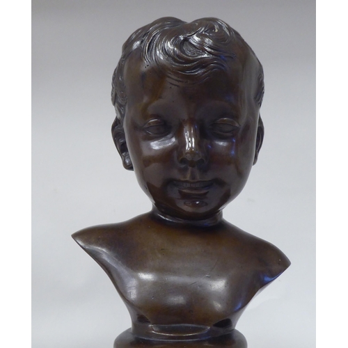 30 - A late 19thC cast and patinated bronze bust, a young boy, on a turned socle  11.5