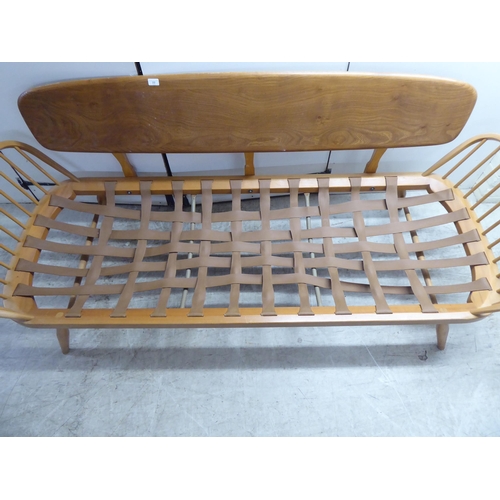 77 - An Ercol blonde elm and beech framed daybed with a solid surfboard back and low hoop and spindled ba... 