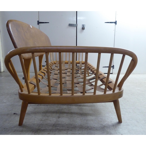 77 - An Ercol blonde elm and beech framed daybed with a solid surfboard back and low hoop and spindled ba... 