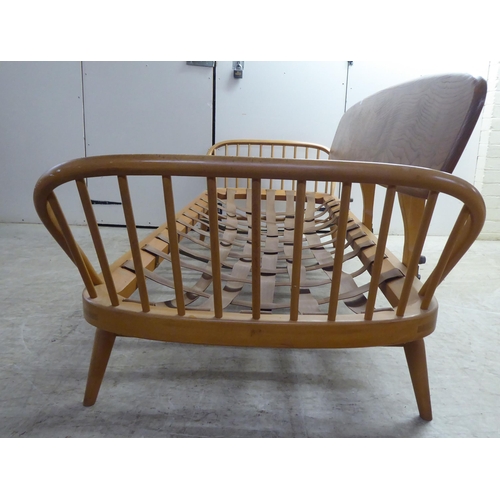 77 - An Ercol blonde elm and beech framed daybed with a solid surfboard back and low hoop and spindled ba... 