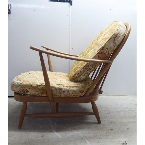 78 - A pair of Ercol blonde elm and beech framed high hoop and spindled back chairs with open arms and lo... 