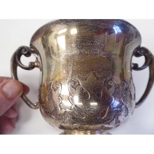 85 - A silver porringer with a flared lip and opposing C-scrolled handles, on a demi-reeded footrim, deco... 