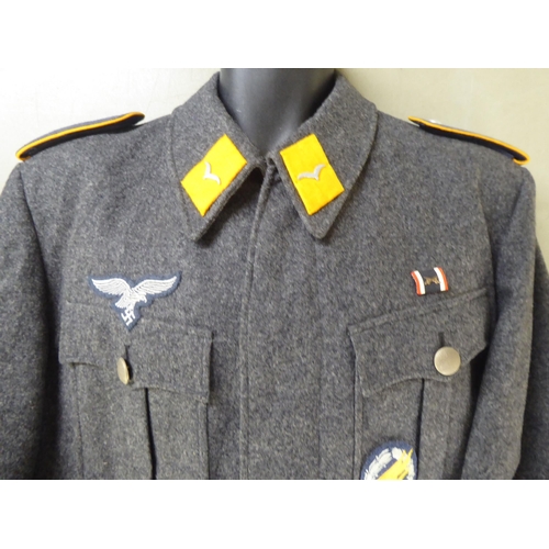 96 - Two dissimilar German World War II style military tunics with emblems(Please Note: this lot is subje... 