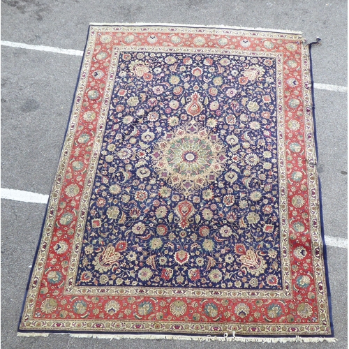 259 - A Persian carpet, decorated with floral and foliate designs, on a mainly dark blue and multi-coloure... 