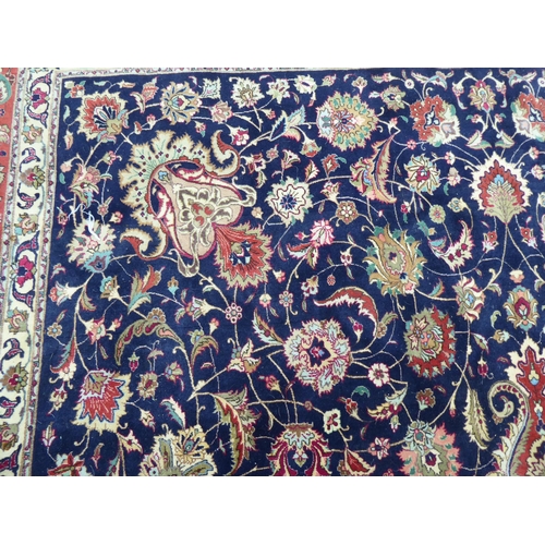 259 - A Persian carpet, decorated with floral and foliate designs, on a mainly dark blue and multi-coloure... 