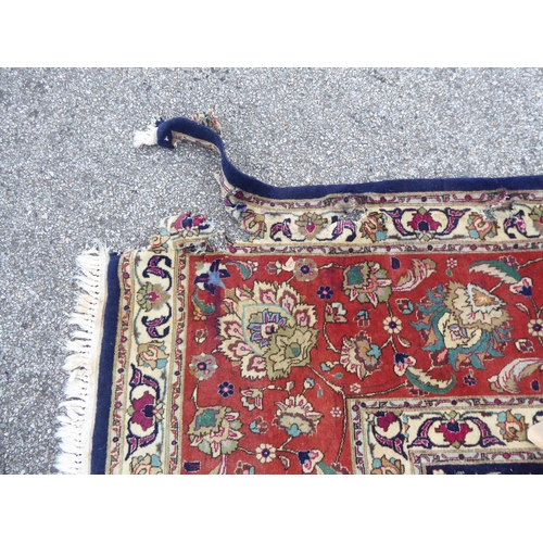 259 - A Persian carpet, decorated with floral and foliate designs, on a mainly dark blue and multi-coloure... 