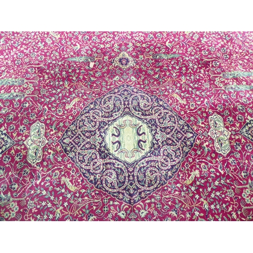 260 - A Persian machine made carpet, profusely traditionally decorated with birds and flora, on a multi-co... 