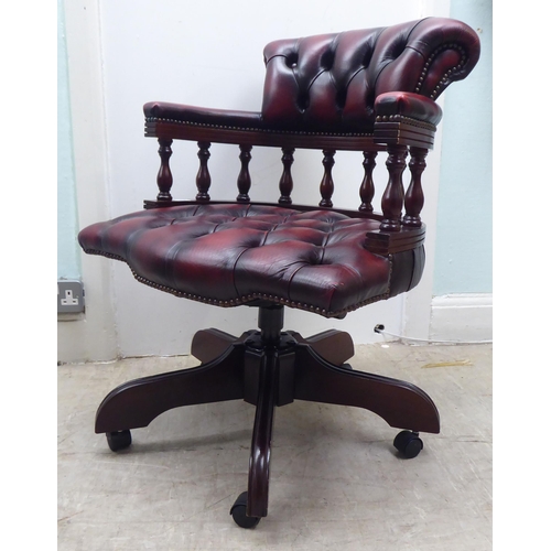 264 - A modern Captains style mahogany showwood framed desk chair, stud and part button upholstered in ox ... 