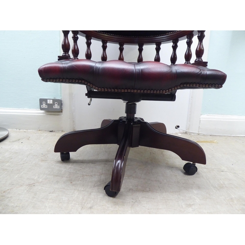 264 - A modern Captains style mahogany showwood framed desk chair, stud and part button upholstered in ox ... 