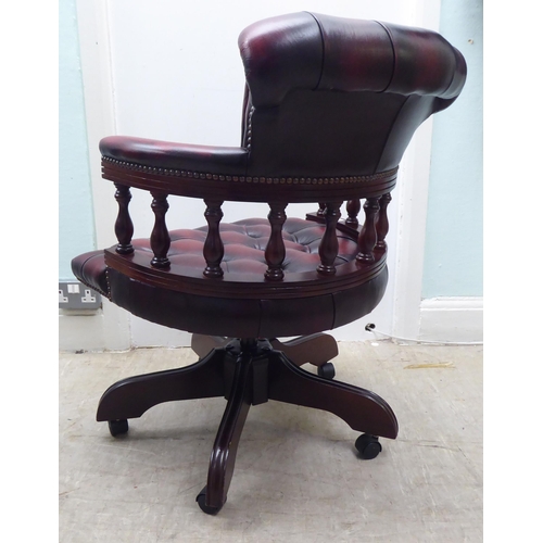 264 - A modern Captains style mahogany showwood framed desk chair, stud and part button upholstered in ox ... 