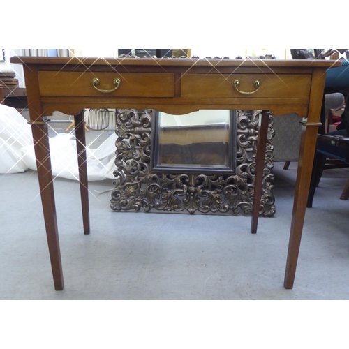 279 - An Edwardian mahogany two drawer writing table, the top set with a black scriber, raised on square l... 