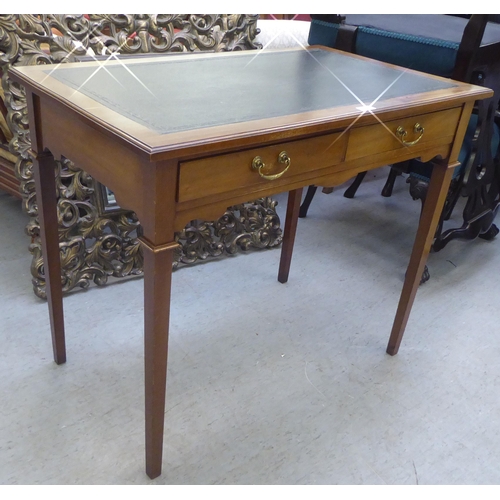 279 - An Edwardian mahogany two drawer writing table, the top set with a black scriber, raised on square l... 