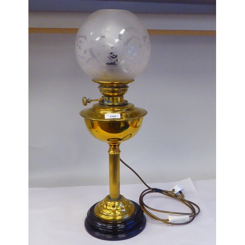 298 - An early 20thC lacquered brass oil lamp (later converted to electricity) with a part-frosted glass b... 