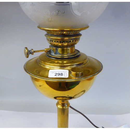 298 - An early 20thC lacquered brass oil lamp (later converted to electricity) with a part-frosted glass b... 