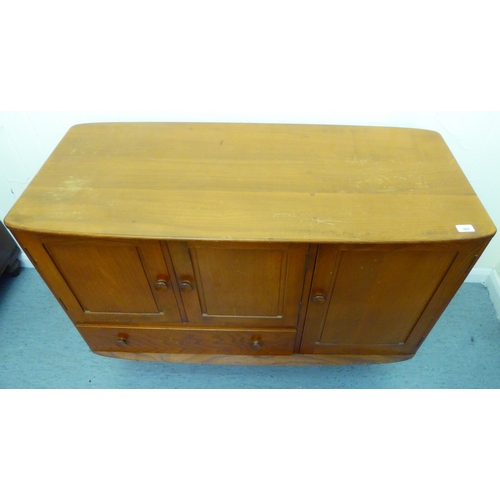 309 - A blonde Ercol elm sideboard with an arrangement of three cupboards and a drawer, raised on tapered ... 