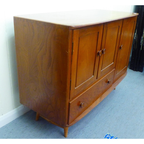 309 - A blonde Ercol elm sideboard with an arrangement of three cupboards and a drawer, raised on tapered ... 