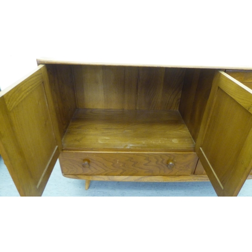 309 - A blonde Ercol elm sideboard with an arrangement of three cupboards and a drawer, raised on tapered ... 