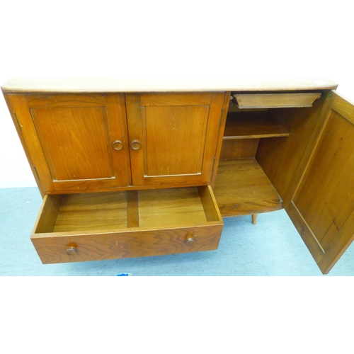 309 - A blonde Ercol elm sideboard with an arrangement of three cupboards and a drawer, raised on tapered ... 