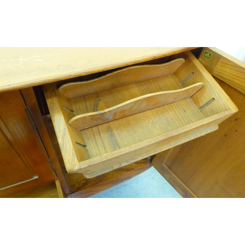 309 - A blonde Ercol elm sideboard with an arrangement of three cupboards and a drawer, raised on tapered ... 