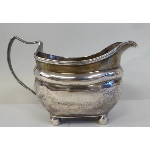 1 - A George III silver oval, ogee shape cream jug with an applied wire rim and loop handle, on ball fee... 