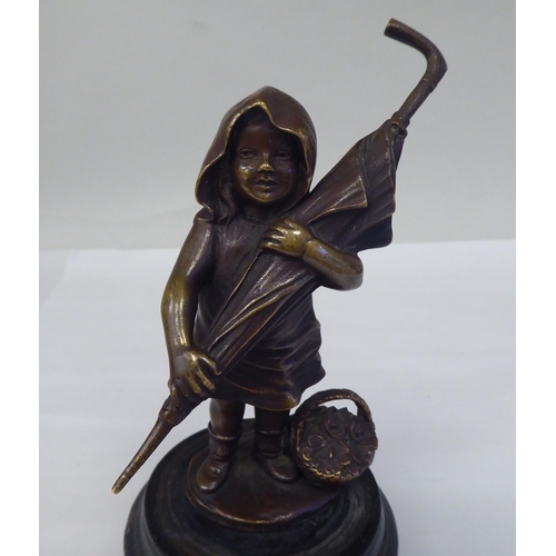 120 - A cast and patinated bronze figure, a little girl carrying an adult's umbrella, on a turned wooden p... 