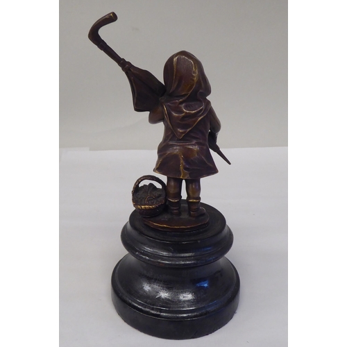 120 - A cast and patinated bronze figure, a little girl carrying an adult's umbrella, on a turned wooden p... 