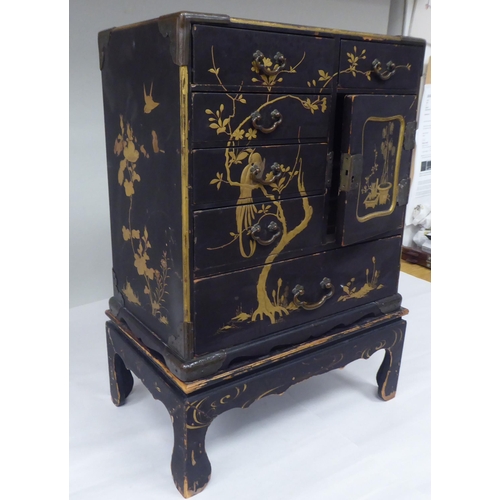 123 - A late 19th/early 20thC Japanese black lacquered and engraved metal mounted, two-part table cabinet,... 