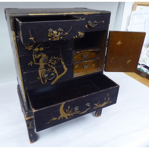 123 - A late 19th/early 20thC Japanese black lacquered and engraved metal mounted, two-part table cabinet,... 