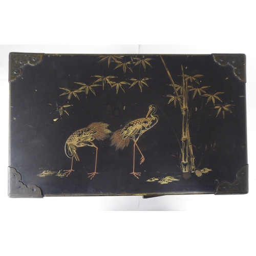 123 - A late 19th/early 20thC Japanese black lacquered and engraved metal mounted, two-part table cabinet,... 