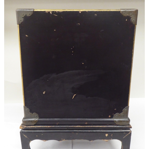 123 - A late 19th/early 20thC Japanese black lacquered and engraved metal mounted, two-part table cabinet,... 