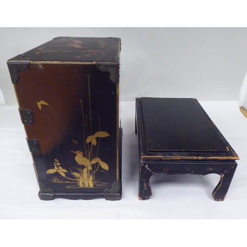 123 - A late 19th/early 20thC Japanese black lacquered and engraved metal mounted, two-part table cabinet,... 