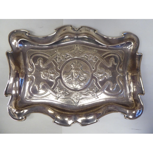 127 - An Art Nouveau period silver four piece dressing table set tray, featuring a maidens crowned portrai... 