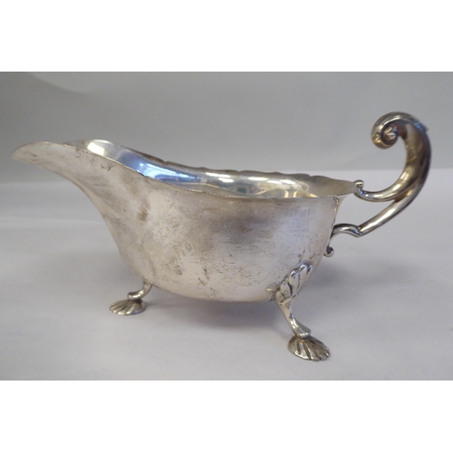 151 - A silver pedestal caster with a domed cover; and a silver sauce boat, having a C-scrolled handle, on... 