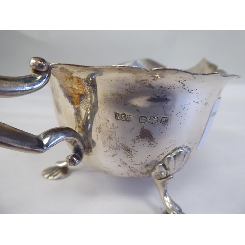 151 - A silver pedestal caster with a domed cover; and a silver sauce boat, having a C-scrolled handle, on... 