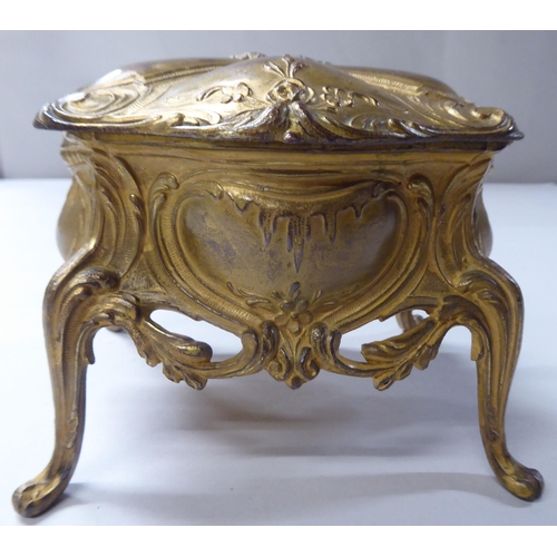 167 - A late 19thC cast gilded metal jewellery box, fashioned as a commode, the hinged lid enclosing a qui... 