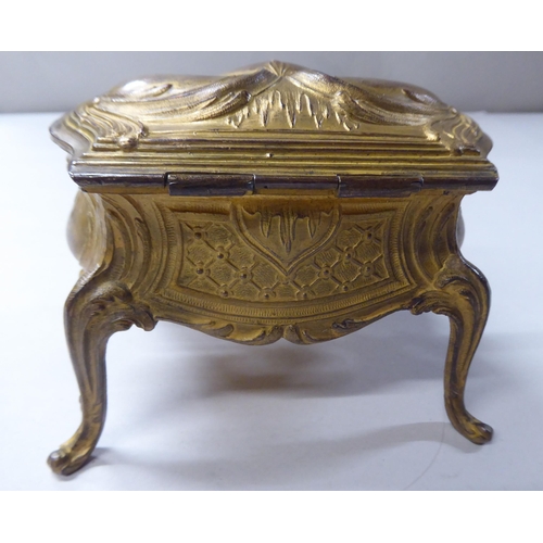 167 - A late 19thC cast gilded metal jewellery box, fashioned as a commode, the hinged lid enclosing a qui... 