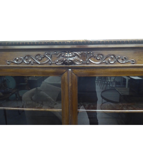 172 - A late Victorian mahogany bookcase with carved mask ornament and two glazed doors, on a plinth ... 