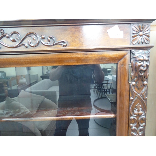 172 - A late Victorian mahogany bookcase with carved mask ornament and two glazed doors, on a plinth ... 