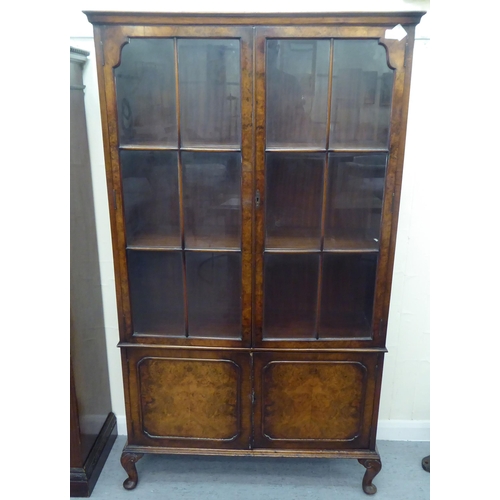 172 - A late Victorian mahogany bookcase with carved mask ornament and two glazed doors, on a plinth ... 