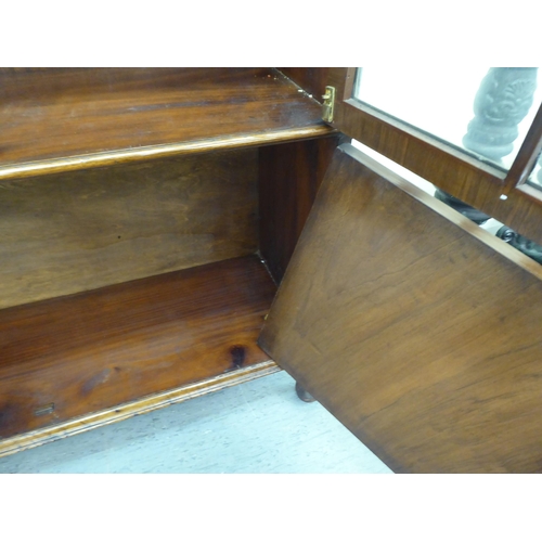 172 - A late Victorian mahogany bookcase with carved mask ornament and two glazed doors, on a plinth ... 