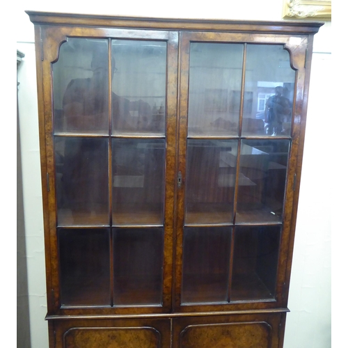 176 - A mid 20thC walnut bookcase with two glazed doors and two panelled doors, raised on cabriole legs&nb... 