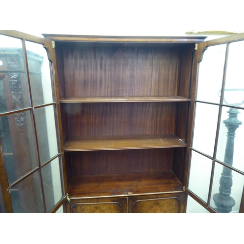 176 - A mid 20thC walnut bookcase with two glazed doors and two panelled doors, raised on cabriole legs&nb... 