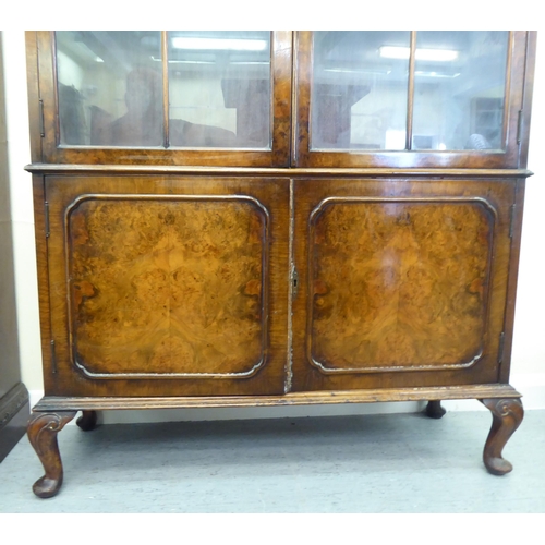 176 - A mid 20thC walnut bookcase with two glazed doors and two panelled doors, raised on cabriole legs&nb... 