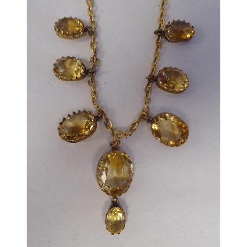 195 - A yellow metal necklace, set with a graduated group of oval cut yellow citrine 