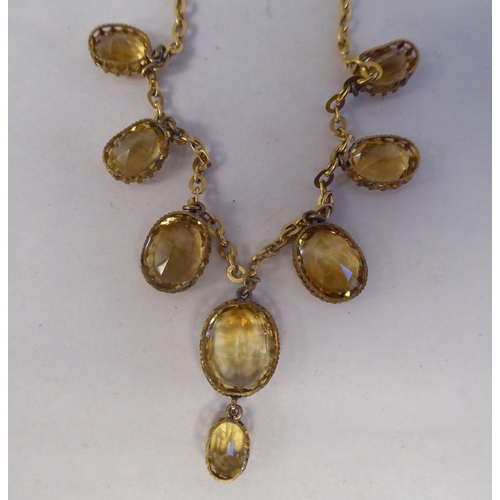 195 - A yellow metal necklace, set with a graduated group of oval cut yellow citrine 