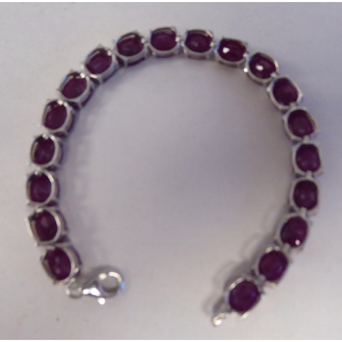 196 - A white metal bracelet, set with rivetted oval cut rubies  stamped 925 